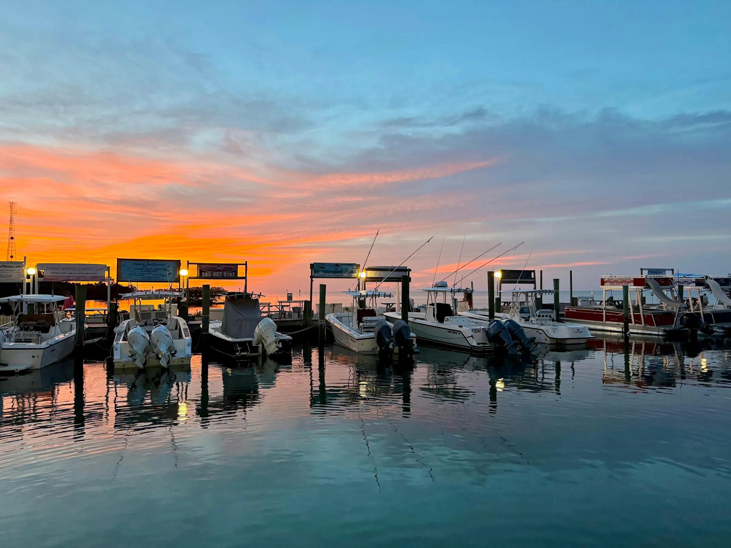 Center-console boats moored along a dock under a pink and orange dusk sky