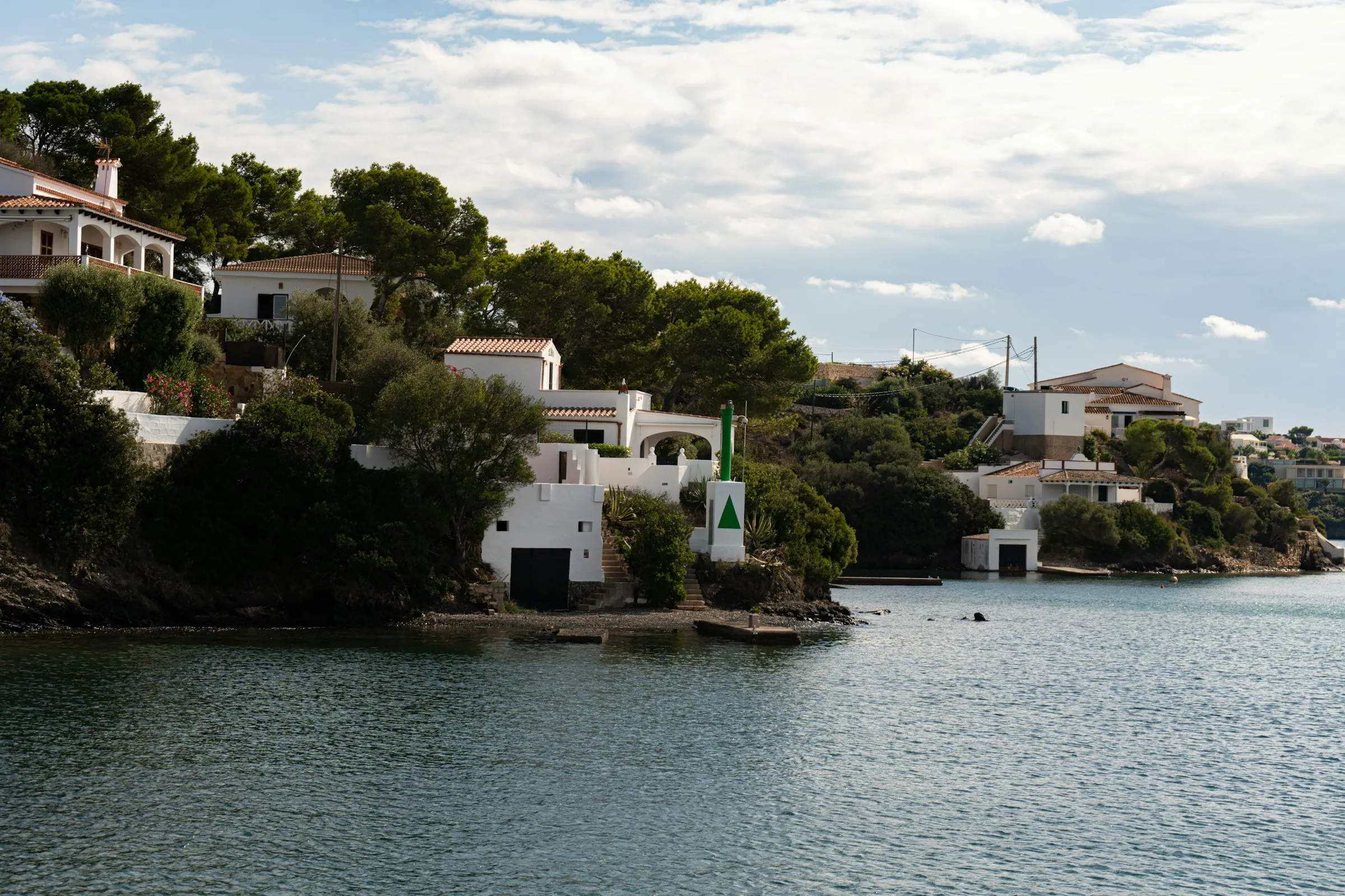 White houses nestled on a green, hilly coastline.